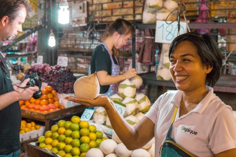 Guide presenting thai coconuts at Khlong Toei market