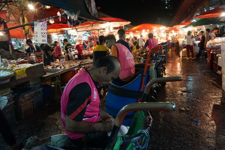 Workers pushing trolleys late at night at Khlong Toei market
