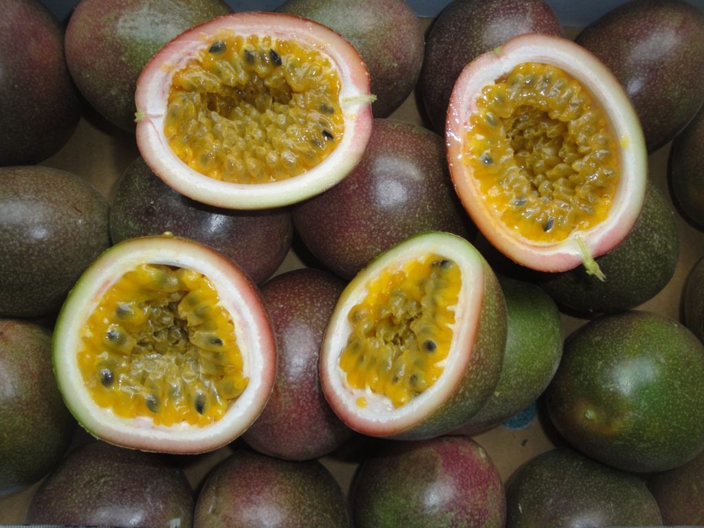 Image of sliced passion fruits with yellow flesh and small black seeds inside   